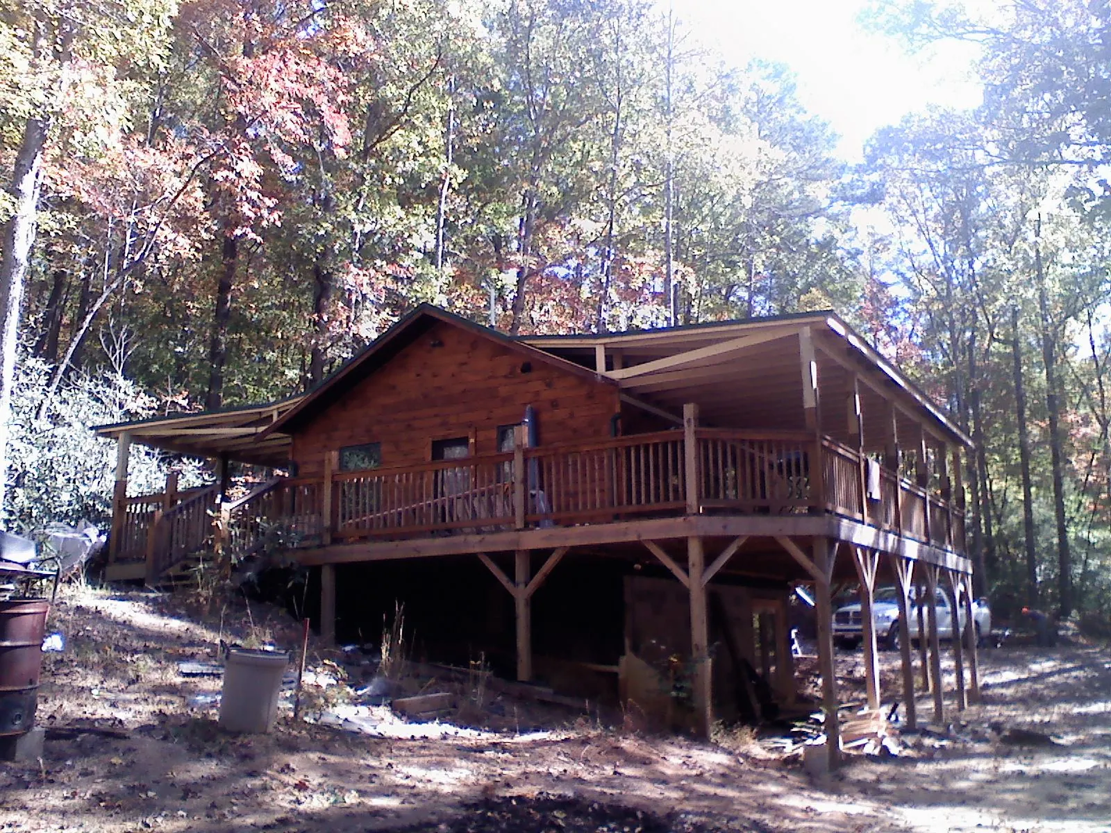 Log cabin with a wraparound porch and metal roof in the fall in Warrenton