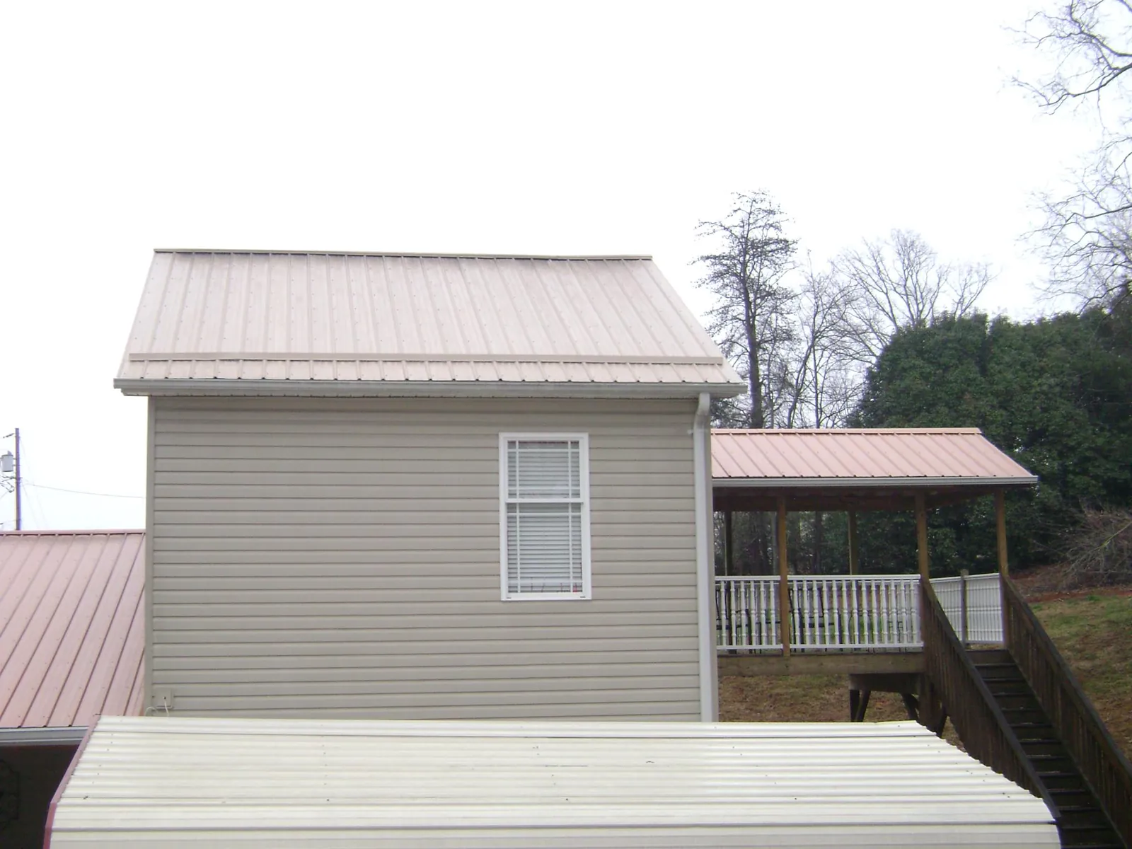 Tan metal roofs on a two story addition and attached porch, from a Roof Replacement job in Warrenton