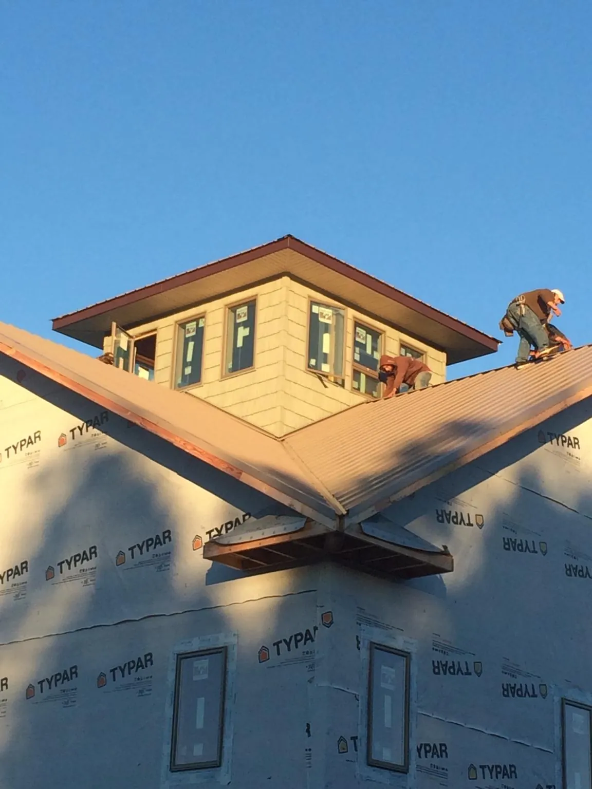 Roofers working around a rooftop cupola on a new metal roof at sunset — Roof Waterproofing in Warrenton by Roofing Brothers